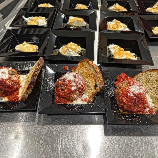 Meatballs with red sauce and grated cheese on toasted bread, alongside small dessert cups.