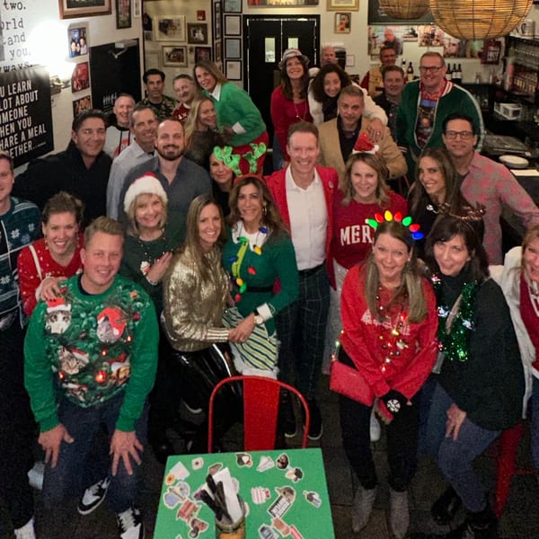 A large group of smiling people in festive holiday attire gathered at Bar Jawn.