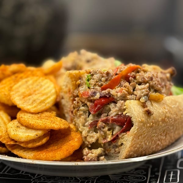 Cheesesteak sandwich with red peppers and onions, served with seasoned waffle-cut chips.