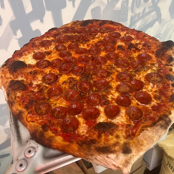 A large, round pepperoni pizza with a crispy crust, rich red sauce, and melted cheese.