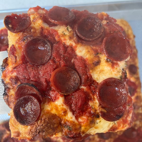 A square slice of Bar Jawn's pepperoni pizza with thick crust and melted cheese.