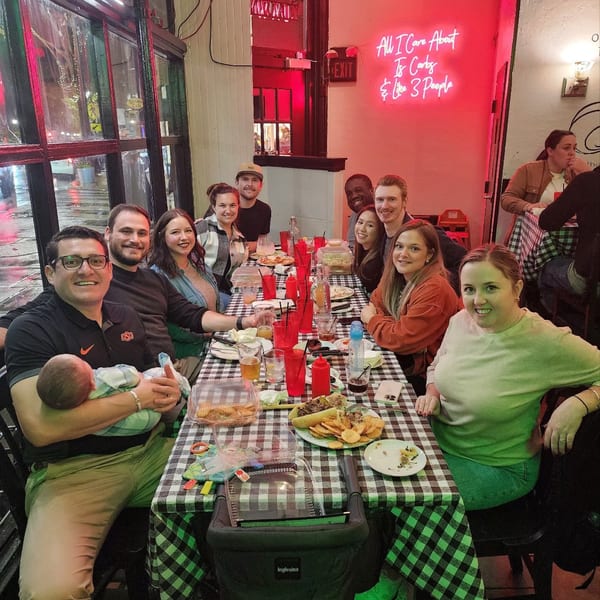 A large group of friends and family, including a baby, enjoying a meal at Bar Jawn.